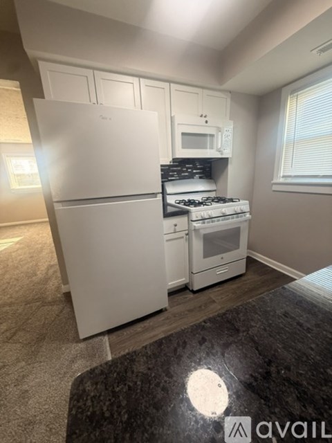 A kitchen with a white fridge, stove, and microwave.