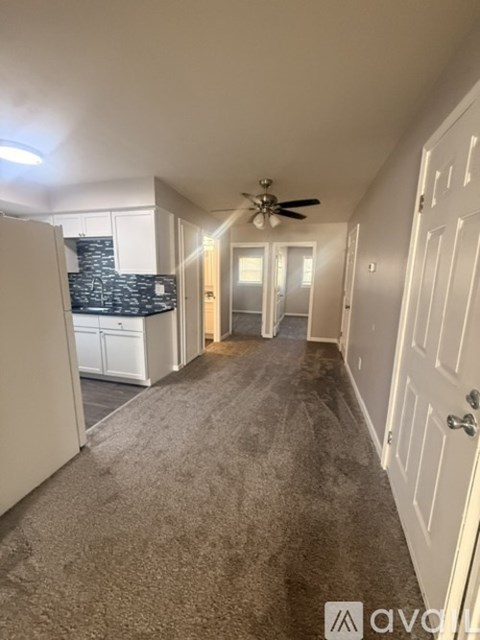 A long hallway with a carpeted floor and a ceiling fan.