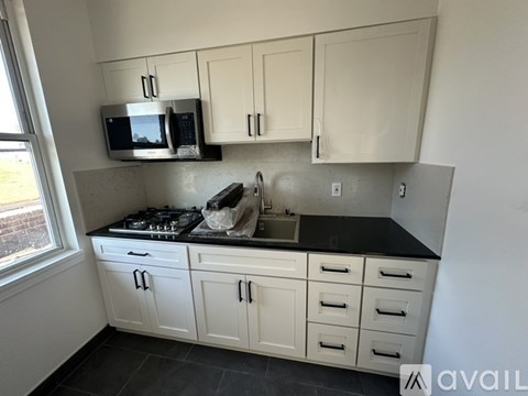 A kitchen with white cabinets and a black countertop.