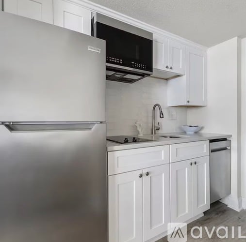 A modern kitchen with white cabinets and stainless steel appliances.