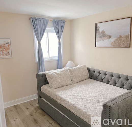 A bedroom with a large bed and a window with curtains.
