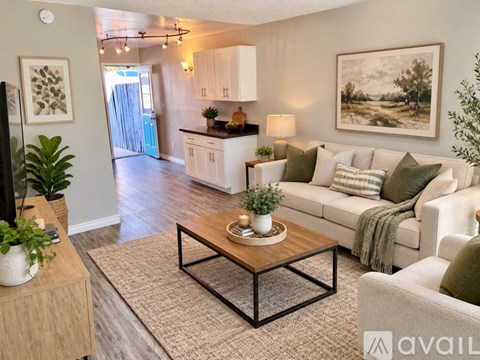 A living room with a white couch, a coffee table, and a painting on the wall.