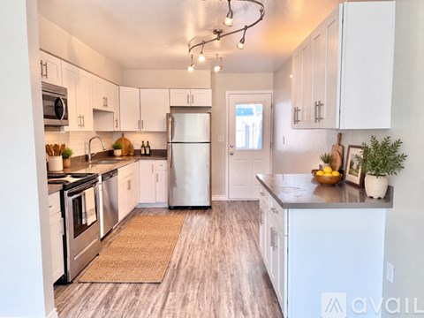 A kitchen with white cabinets and a refrigerator.