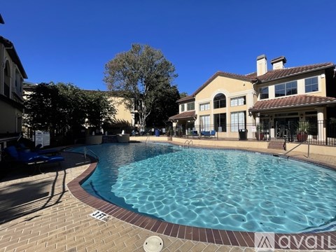 A large swimming pool in front of a building with a blue sky in the background.