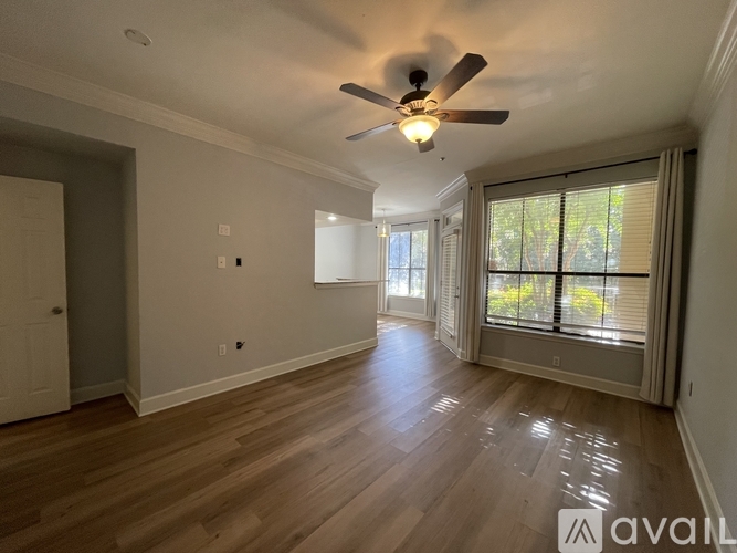A spacious room with wooden floors and a ceiling fan.