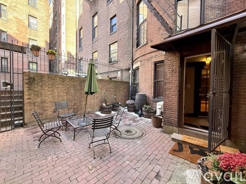 A patio with a table and chairs is surrounded by brick buildings.