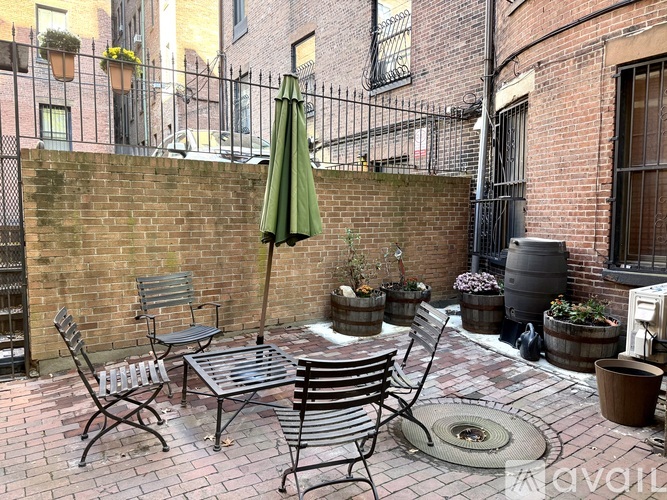 A patio with a table, chairs, and an umbrella.