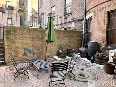 A patio with a table, chairs, and an umbrella.
