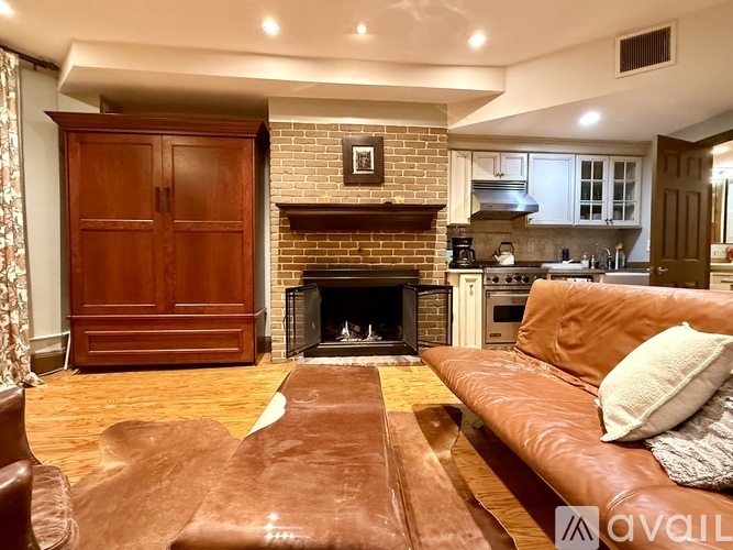 A living room with a brown leather couch and a fireplace.