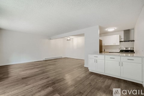 A kitchen area with white cabinets and a wooden floor.