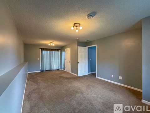 A spacious room with a carpeted floor and a ceiling fan.