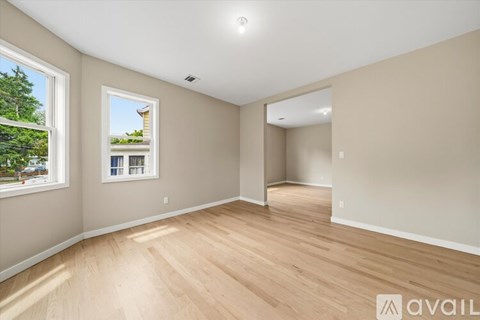 A spacious room with wooden flooring and a large window.