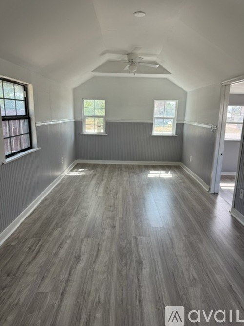 A spacious room with grey flooring and a ceiling fan.