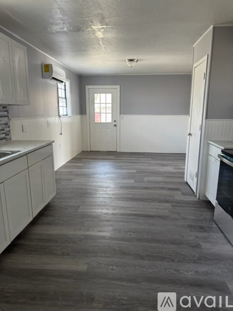 A kitchen with white cabinets and a wooden floor.