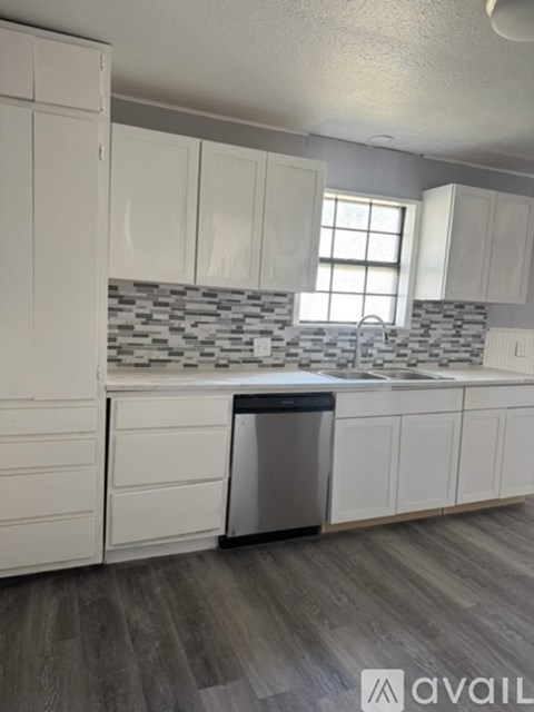 A kitchen with white cabinets and a grey backsplash.