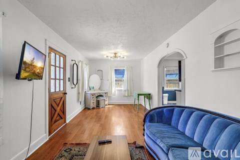 A living room with a blue couch and a television on the wall.