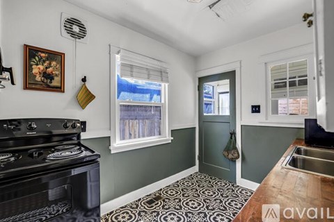A kitchen with a black stove top oven and a green door.