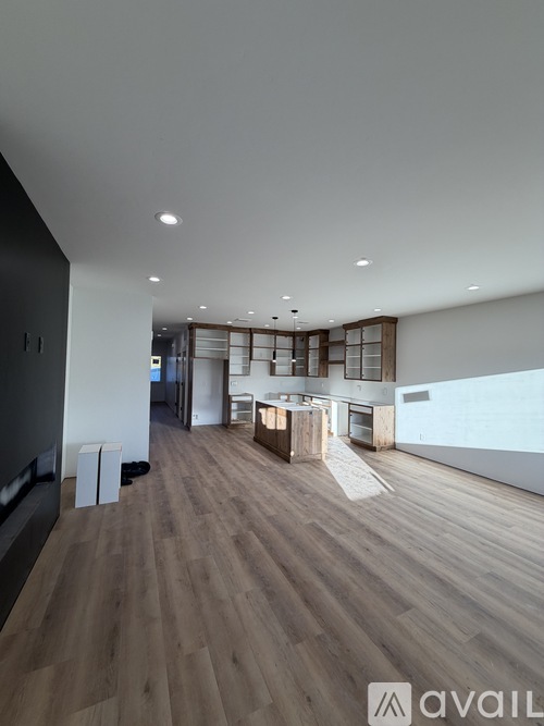 A spacious room with wooden flooring and a large window.