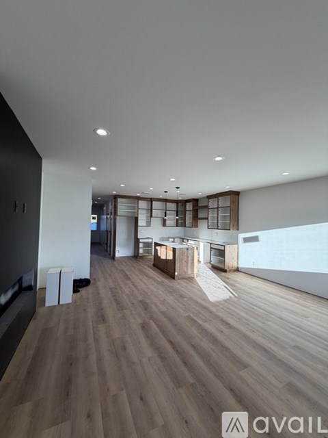 A spacious room with wooden flooring and a large window.