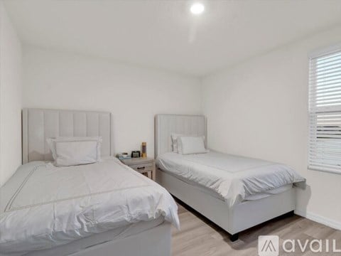 Two white beds in a room with a window.