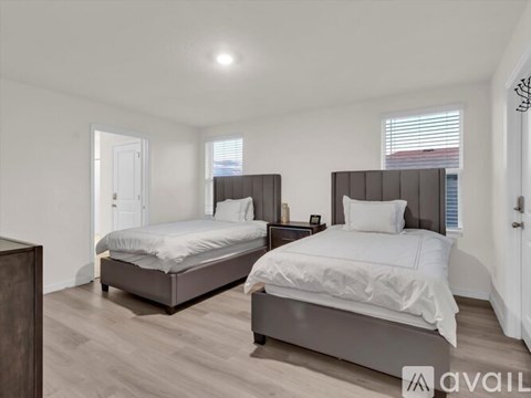 Two beds in a room with wooden floors and white walls.