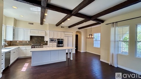 A spacious kitchen with white cabinets and a wooden ceiling.