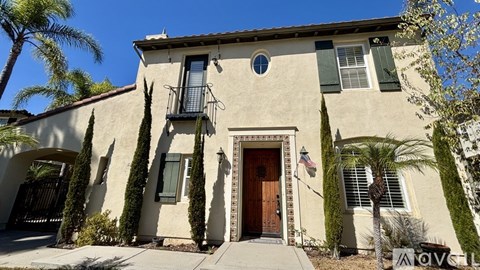 A beige house with a brown door and green shutters.