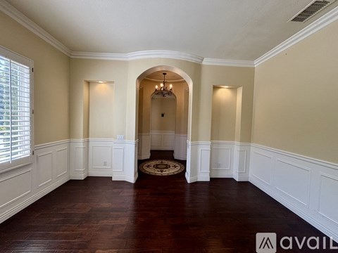 A room with a chandelier and a rug in the middle.