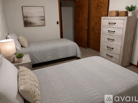 A bedroom with two beds, a nightstand, and a dresser.
