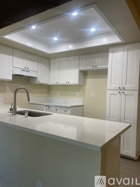 A kitchen with white cabinets and a sink under a faucet.