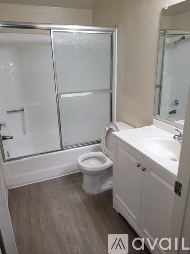 A white bathroom with a toilet, sink, and shower.
