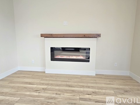 A wood fireplace with a white mantle and a wood beam above it.