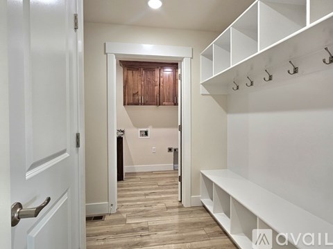 A white door is open to a hallway with a bench and hooks on the wall.