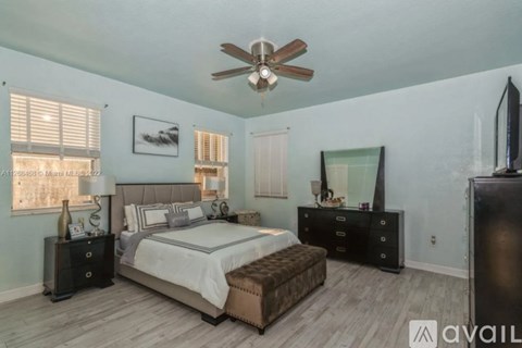 A bedroom with a large bed, a dresser, and a ceiling fan.