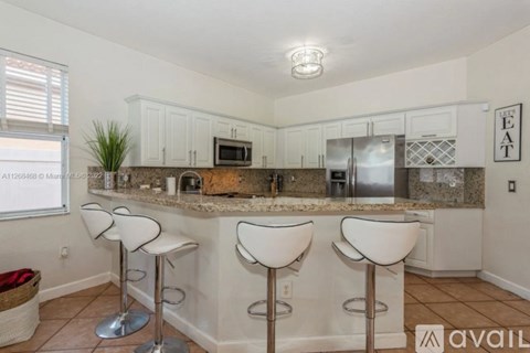 A kitchen with white cabinets and a granite countertop.