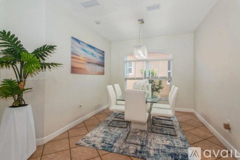 A dining room with a table and chairs and a plant.
