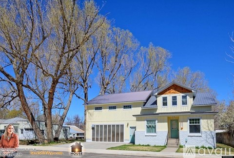 A house with a blue roof and a green door is for sale.