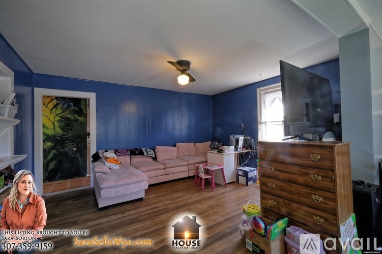 A living room with a blue wall and a television on the right side.