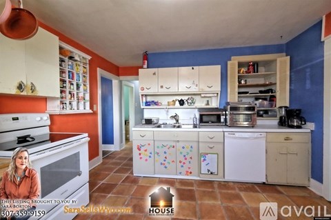 A kitchen with a white stove top oven and white cabinets.