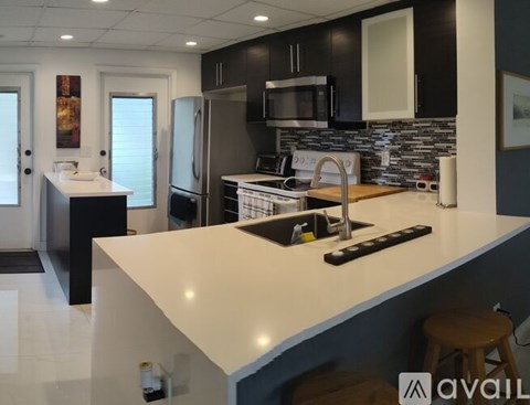 A kitchen with a white counter top and black cabinets.