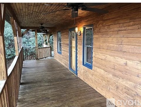 A wooden deck with a ceiling fan and a door.