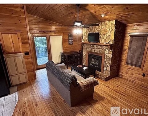 A living room with wood floors and a stone fireplace.