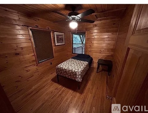 A bedroom with wooden walls and a bed in the center.