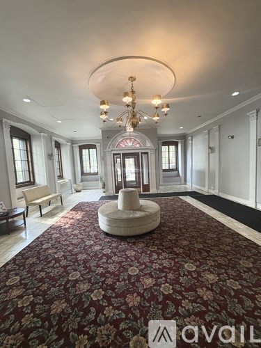 A large, ornate chandelier hangs over a floral carpet in a spacious room.