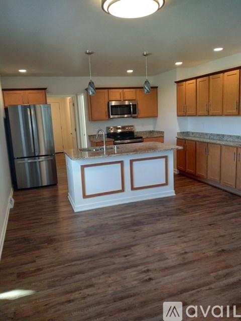 A kitchen with wooden floors and a white island in the middle.