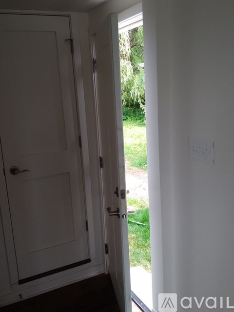 A white door with a handle and a keyhole is open to a grassy area.