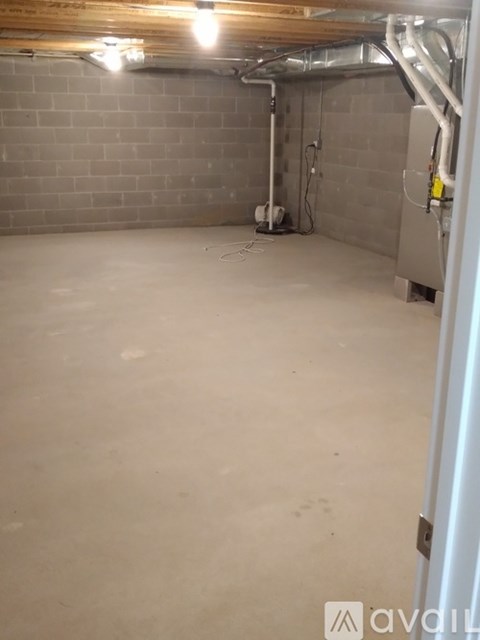 A spacious, unfinished basement with concrete floors and exposed pipes.