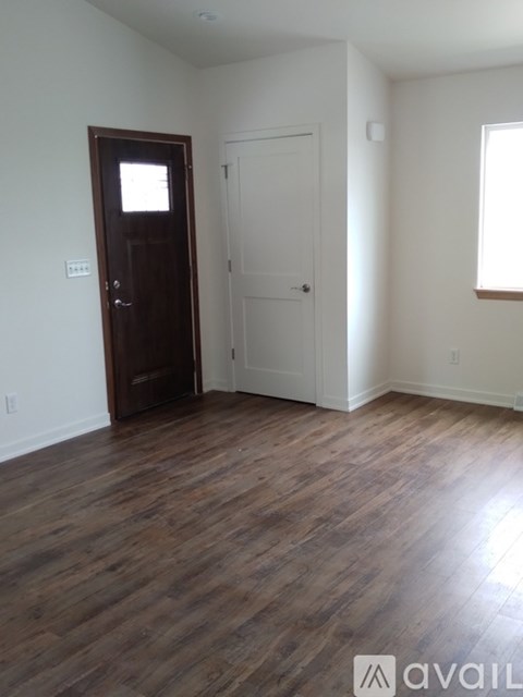 A room with a wooden floor and a brown door.