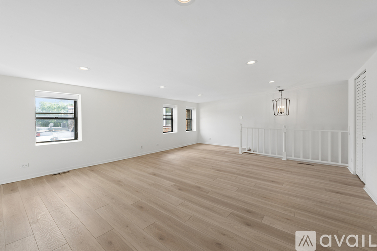 A spacious room with wooden flooring and white walls.