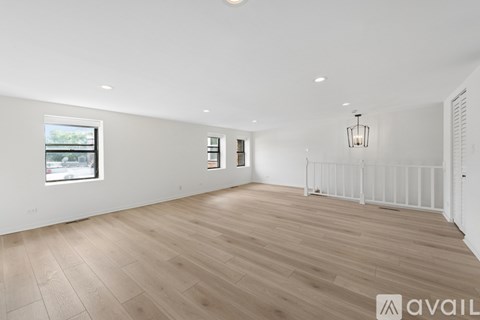 A spacious room with wooden flooring and white walls.